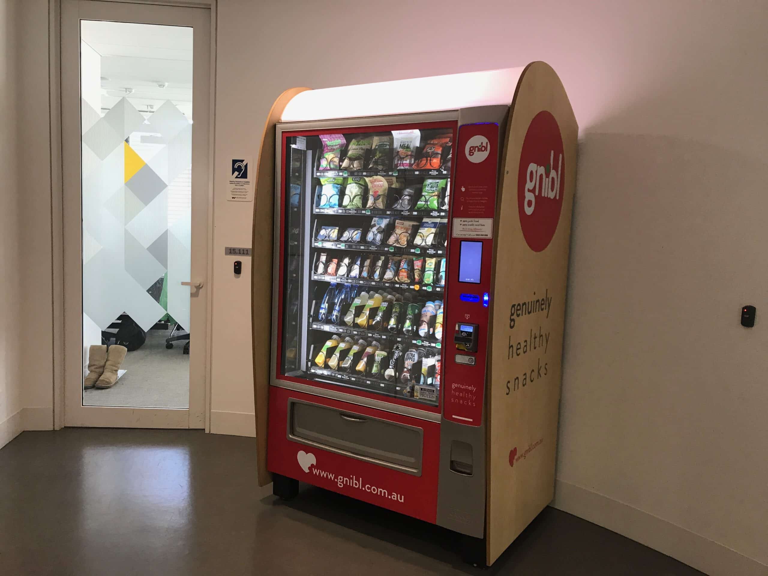 A Gnibl healthy vending machine in a workplace setting, stocked with snack options.