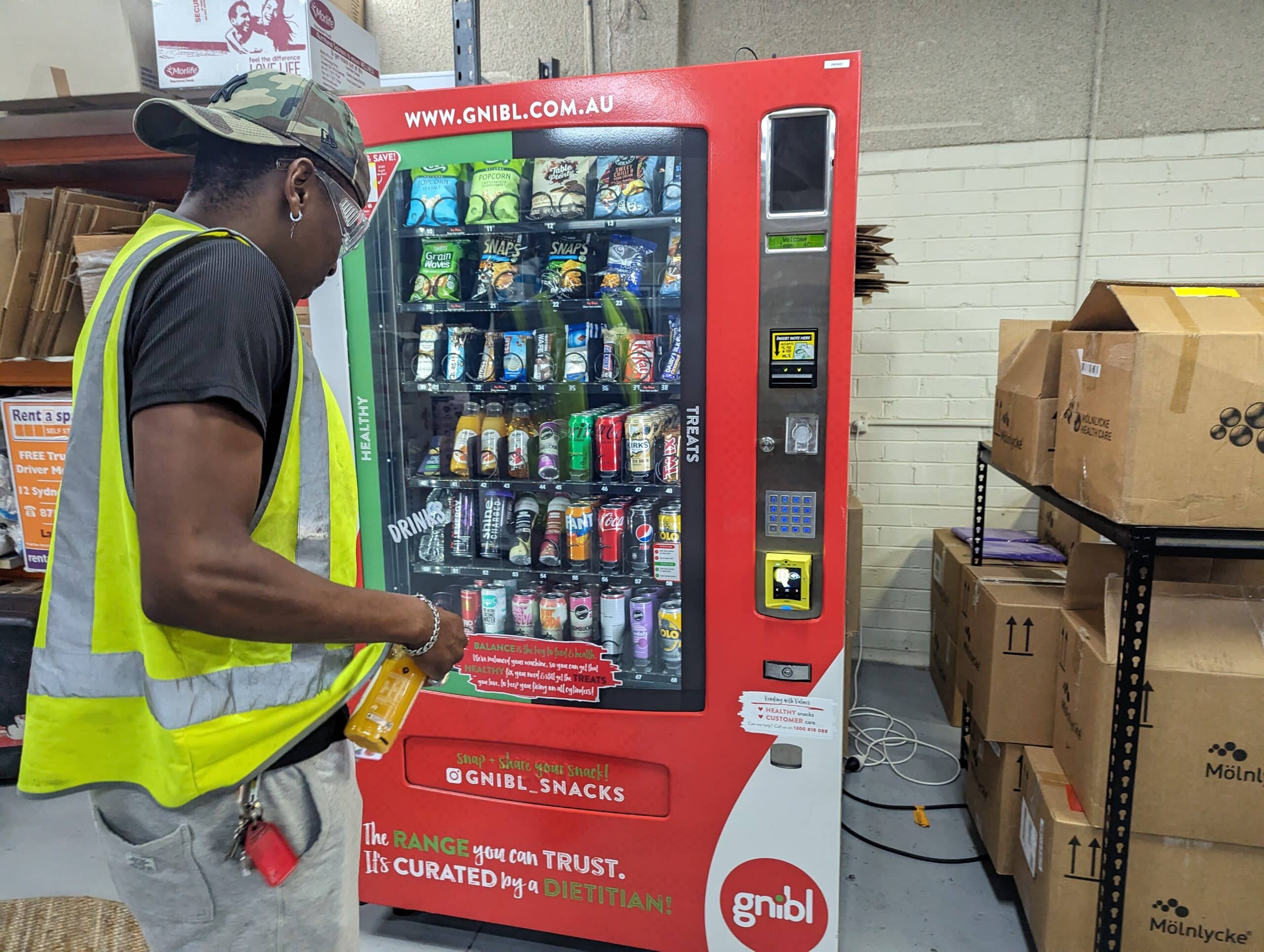 Man with high vis vest using a Gnibl vending machine in warehouse