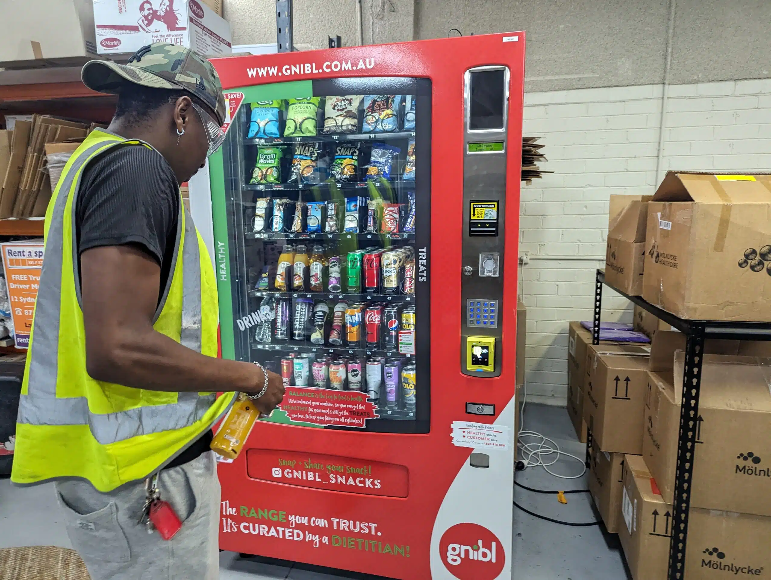 Man with high vis vest using a Gnibl vending machine in warehouse